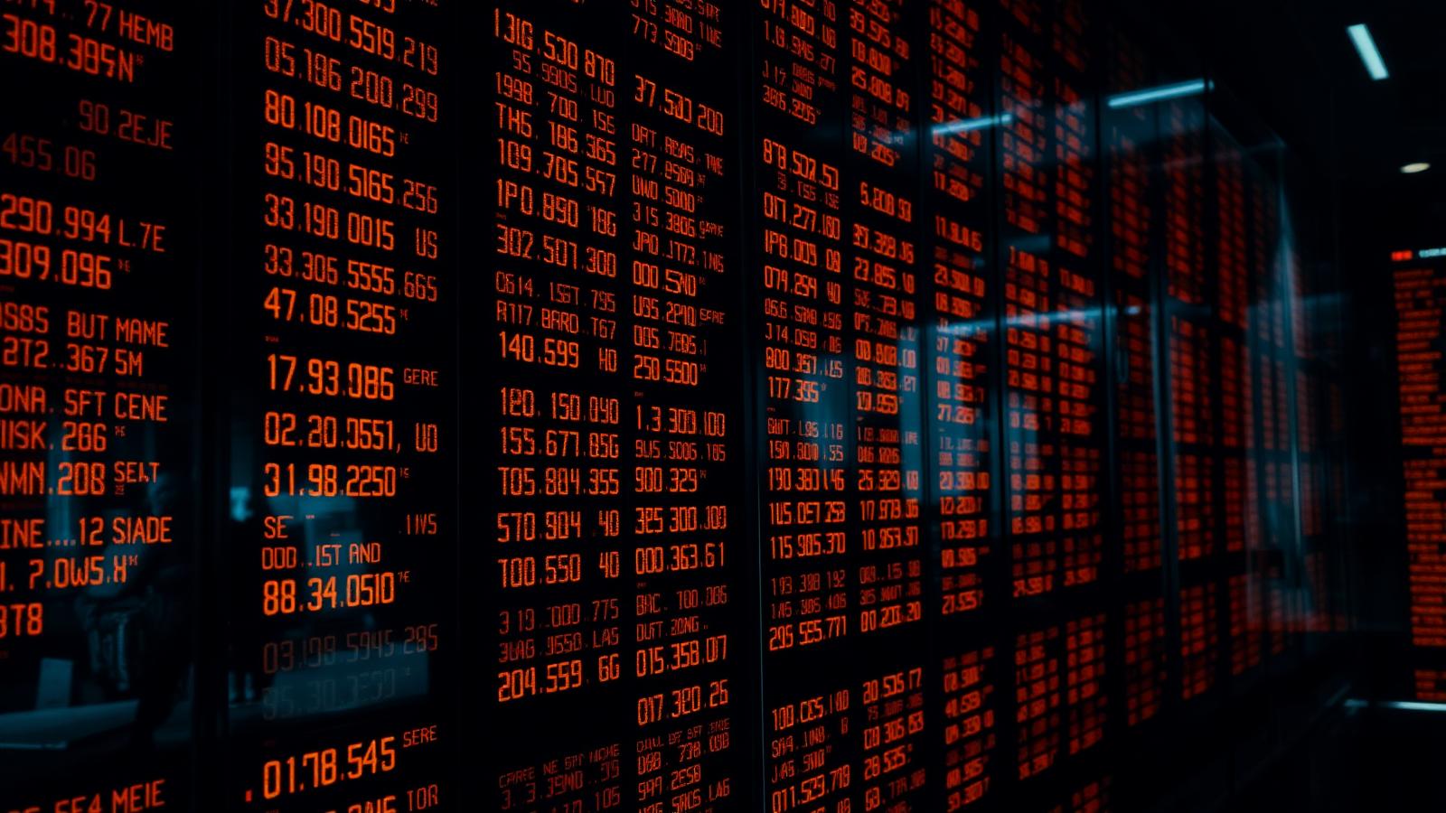 Rows of illuminated financial ticker boards in a darkened trading floor